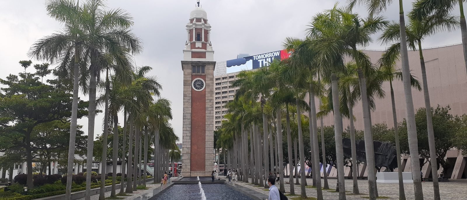 The red and green Haiphong Road Temporary Market building in Tsim Sha Tsui, a traditional gate-arch entrance beside pedestrians on the street.